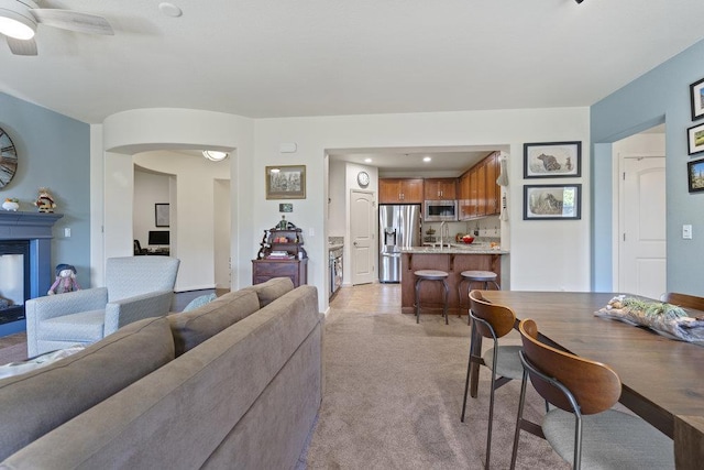 carpeted living room featuring a multi sided fireplace and ceiling fan