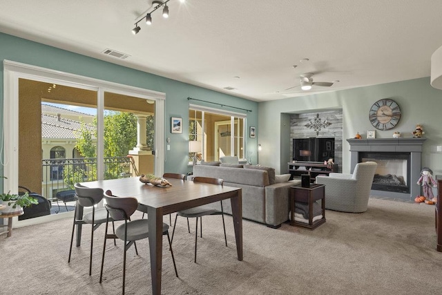 carpeted dining space with track lighting and ceiling fan