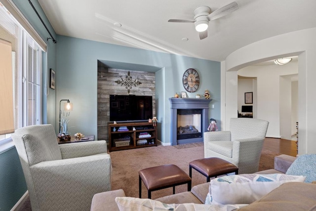 carpeted living room featuring a multi sided fireplace and ceiling fan