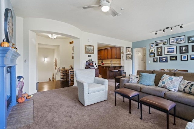 carpeted living room with rail lighting and ceiling fan