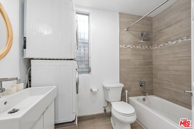 full bathroom with toilet, stacked washing maching and dryer, tiled shower / bath combo, and sink