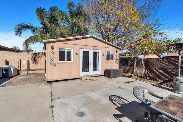 view of outbuilding featuring a fenced backyard, an outdoor structure, and french doors