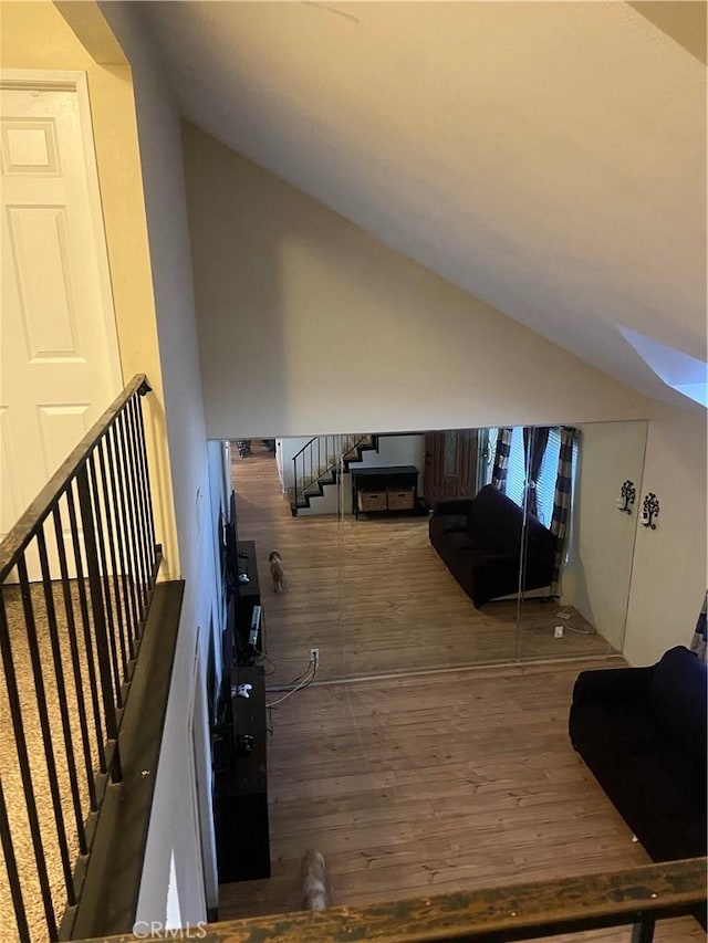 additional living space featuring stairway, wood finished floors, and lofted ceiling