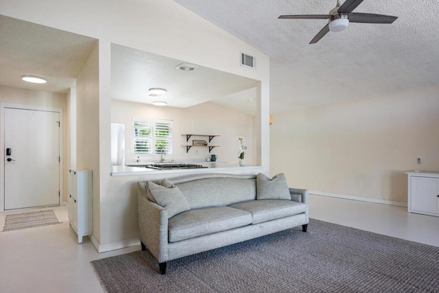 living room featuring a textured ceiling, ceiling fan, and vaulted ceiling