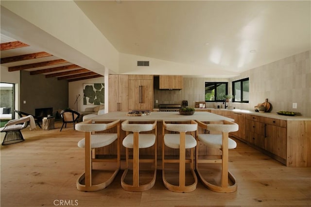 kitchen featuring lofted ceiling with beams, light wood-type flooring, sink, and range