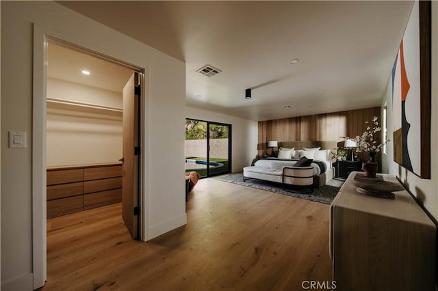 bedroom featuring a spacious closet, a closet, access to outside, and light hardwood / wood-style flooring