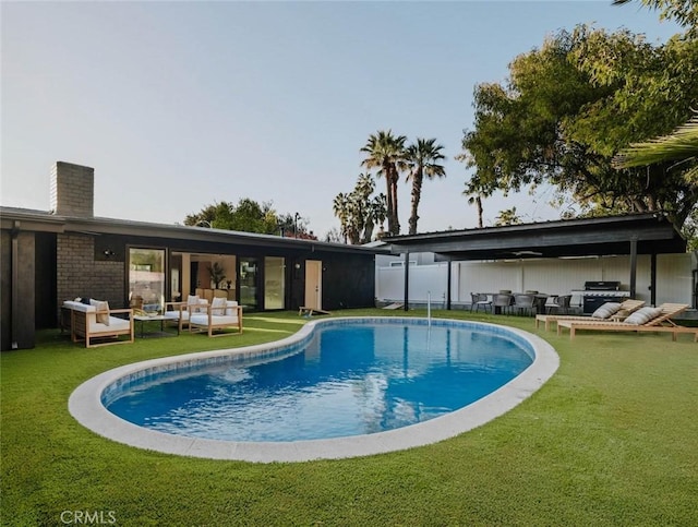 view of swimming pool featuring a lawn, an outdoor living space, and a grill