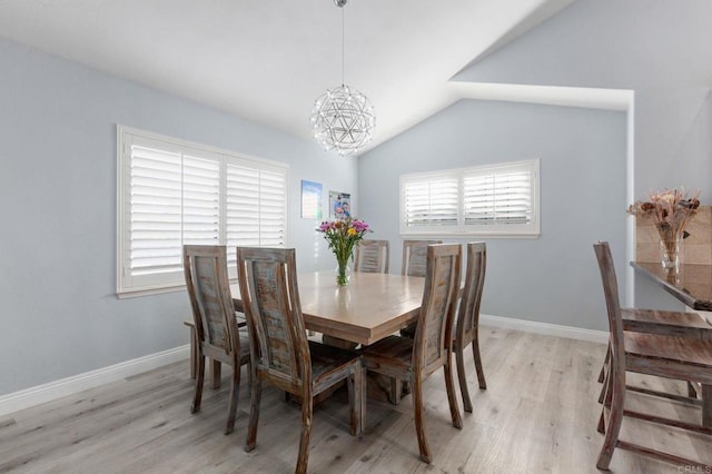 dining space with light hardwood / wood-style floors, a chandelier, and vaulted ceiling