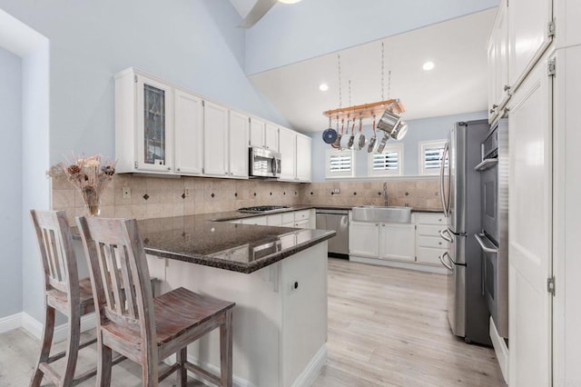 kitchen featuring kitchen peninsula, sink, white cabinets, a breakfast bar area, and stainless steel appliances