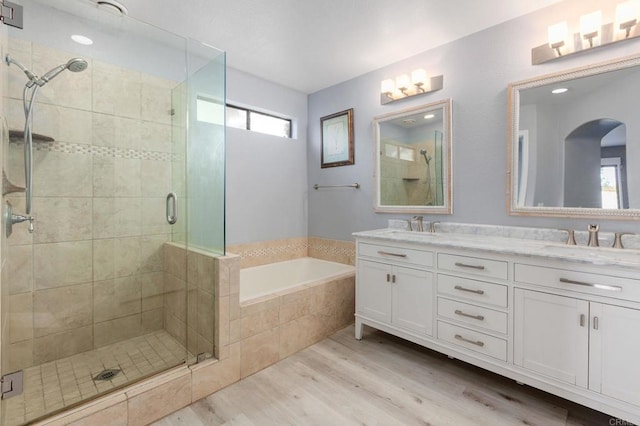 bathroom featuring wood-type flooring, vanity, and plus walk in shower