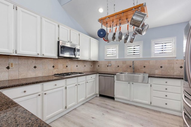 kitchen featuring appliances with stainless steel finishes, white cabinetry, decorative backsplash, sink, and dark stone counters