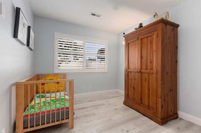 bedroom with a crib and light wood-type flooring