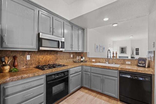 kitchen featuring sink, gray cabinetry, backsplash, and black appliances