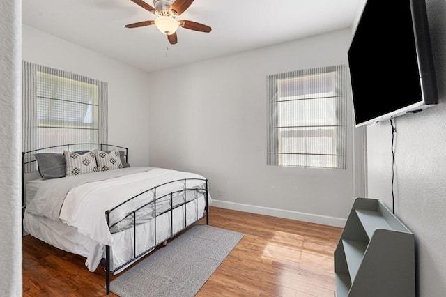 bedroom with ceiling fan, multiple windows, and wood-type flooring