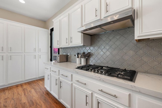 kitchen featuring white cabinetry, tasteful backsplash, hardwood / wood-style flooring, light stone counters, and stainless steel gas stovetop