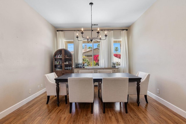 dining space with hardwood / wood-style flooring and a chandelier