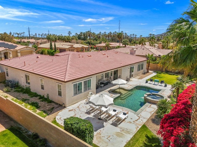 exterior space with a swimming pool with hot tub, central air condition unit, and a patio