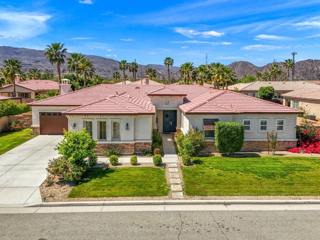 view of front facade with a mountain view, a front yard, and a garage