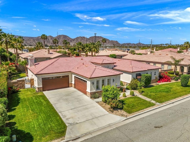 view of front of property featuring a mountain view, a front yard, and a garage