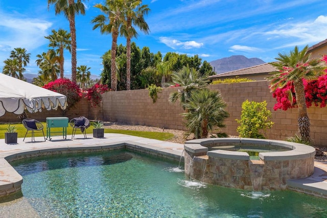 view of swimming pool featuring pool water feature, a mountain view, and an in ground hot tub