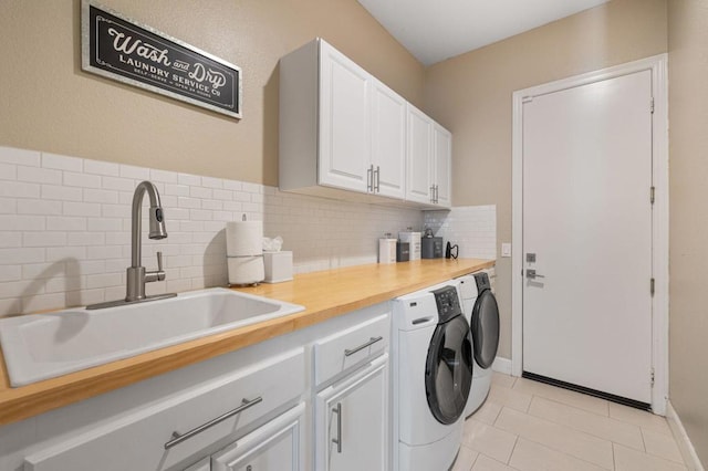 clothes washing area with light tile patterned floors, cabinets, washer and dryer, and sink