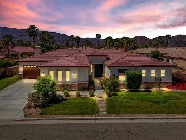 view of front facade with a garage, a mountain view, and a yard