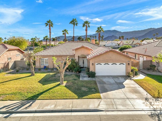 view of front facade featuring a front yard, a garage, and a mountain view