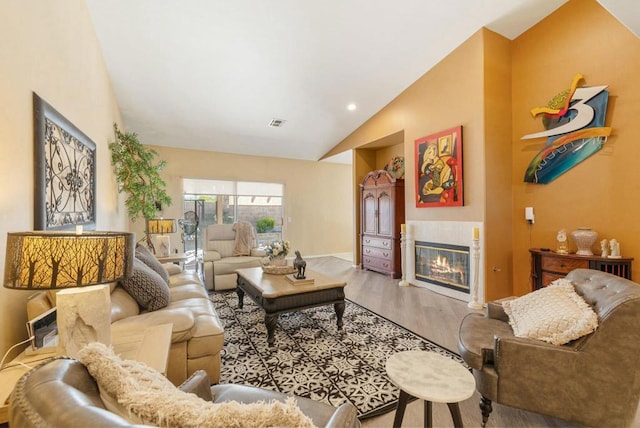 living room with wood-type flooring, high vaulted ceiling, and a fireplace