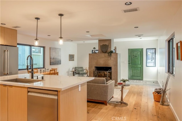 kitchen with visible vents, a sink, open floor plan, and stainless steel dishwasher