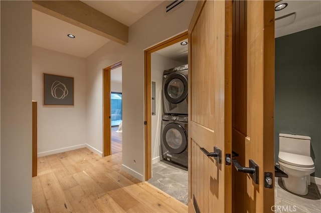 hall with light hardwood / wood-style floors, stacked washer / drying machine, and beamed ceiling