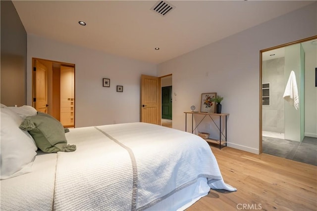 bedroom with ensuite bathroom and light wood-type flooring