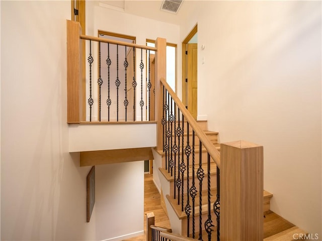 stairway with visible vents and wood finished floors