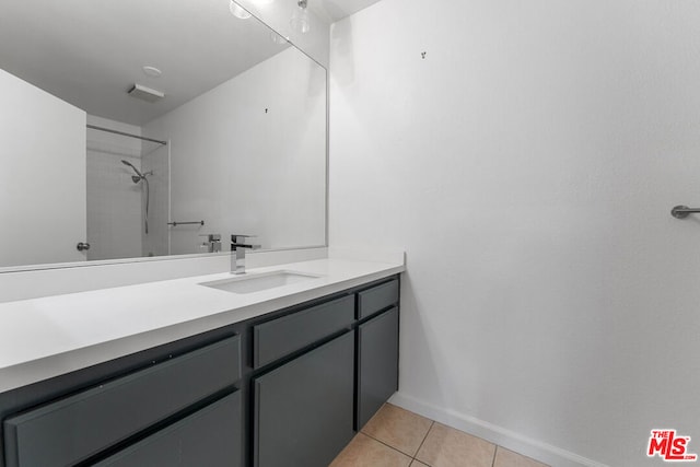 bathroom with tile patterned floors, vanity, and a tile shower