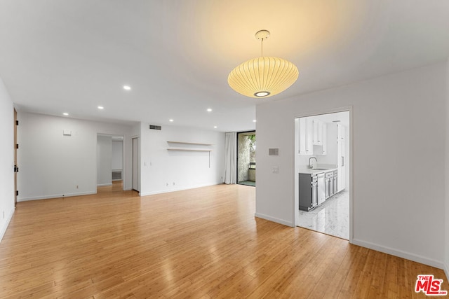 unfurnished living room featuring light hardwood / wood-style floors and sink