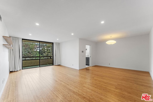 unfurnished living room featuring floor to ceiling windows and light wood-type flooring