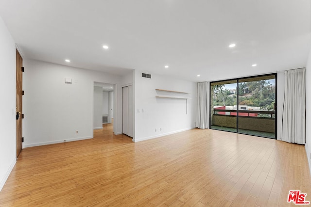 unfurnished living room featuring a wall of windows and light wood-type flooring