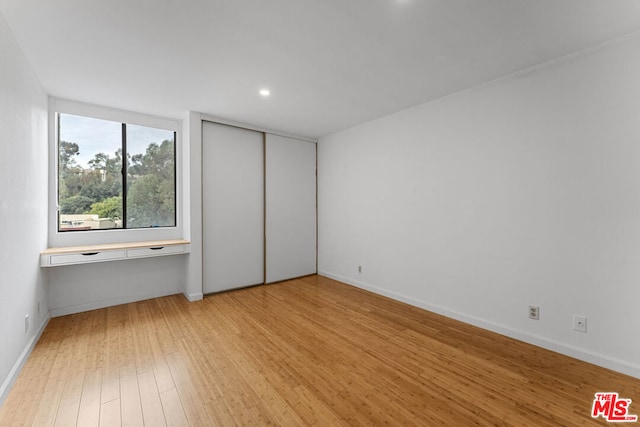 unfurnished bedroom featuring a closet and hardwood / wood-style floors