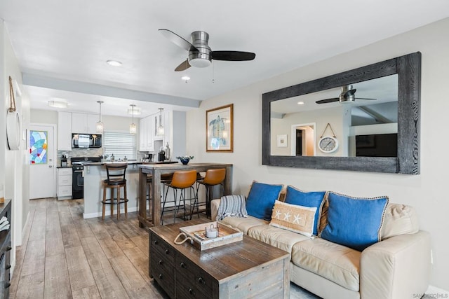 living room with light wood-type flooring and ceiling fan