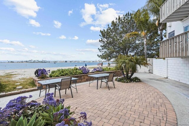 view of patio / terrace featuring a water view and a beach view