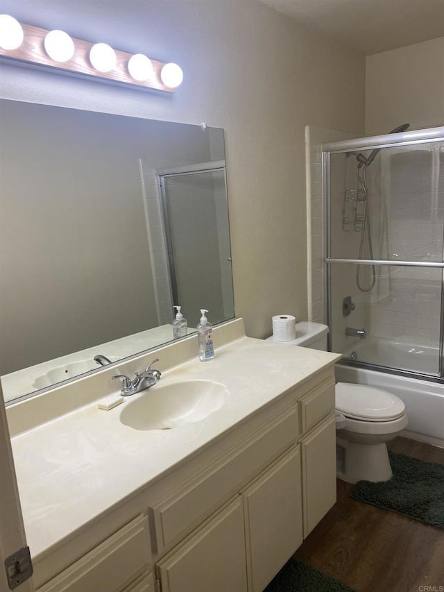 full bathroom with toilet, bath / shower combo with glass door, wood-type flooring, and vanity