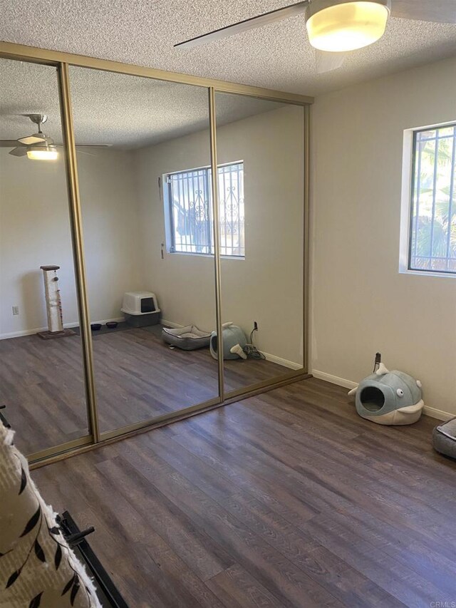 unfurnished bedroom with a textured ceiling, a closet, dark hardwood / wood-style flooring, and ceiling fan