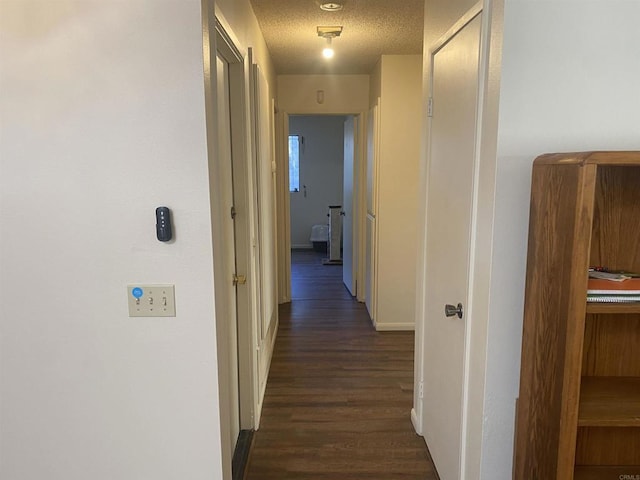 hall with dark wood-type flooring and a textured ceiling