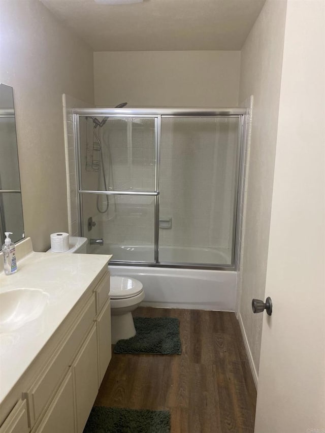 full bathroom featuring toilet, vanity, wood-type flooring, and shower / bath combination with glass door