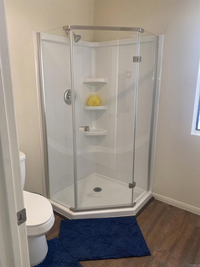 bathroom featuring hardwood / wood-style flooring, toilet, and a shower with shower door