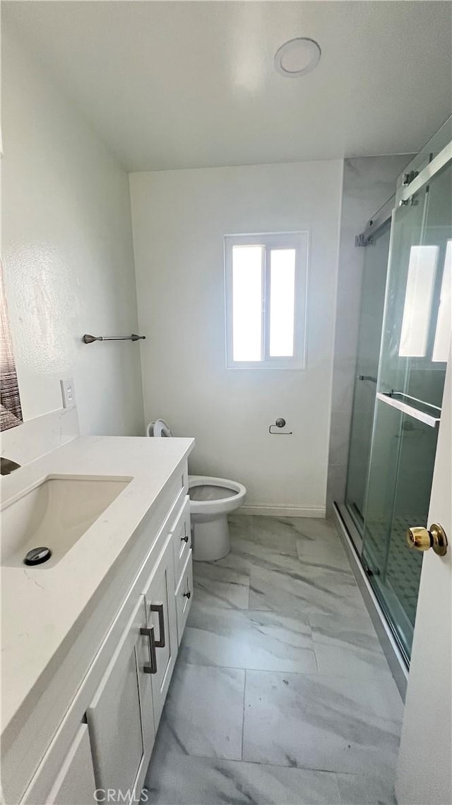 bathroom with toilet, vanity, and a shower with door