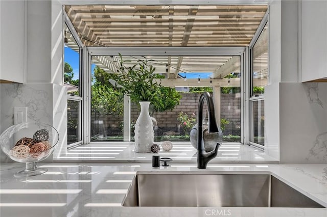 details featuring light stone countertops, decorative backsplash, and sink