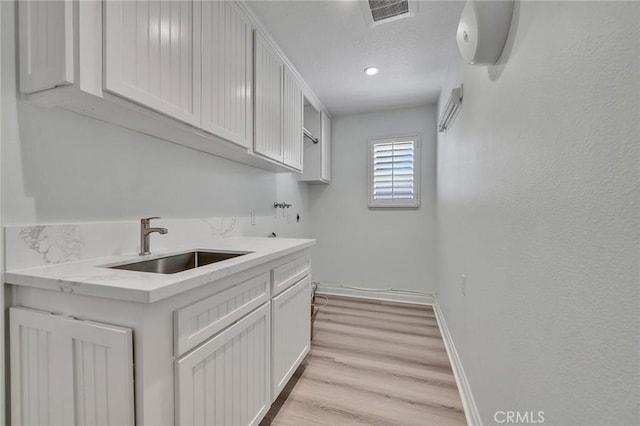 laundry area with cabinets, sink, light hardwood / wood-style flooring, and washer hookup