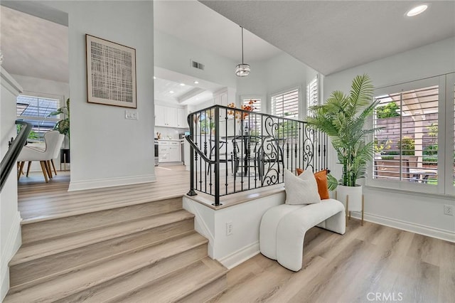 stairway with a healthy amount of sunlight, a notable chandelier, and hardwood / wood-style floors