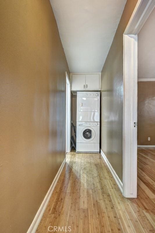 hallway featuring stacked washer and clothes dryer and light hardwood / wood-style flooring