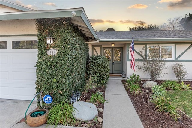 exterior entry at dusk featuring a garage